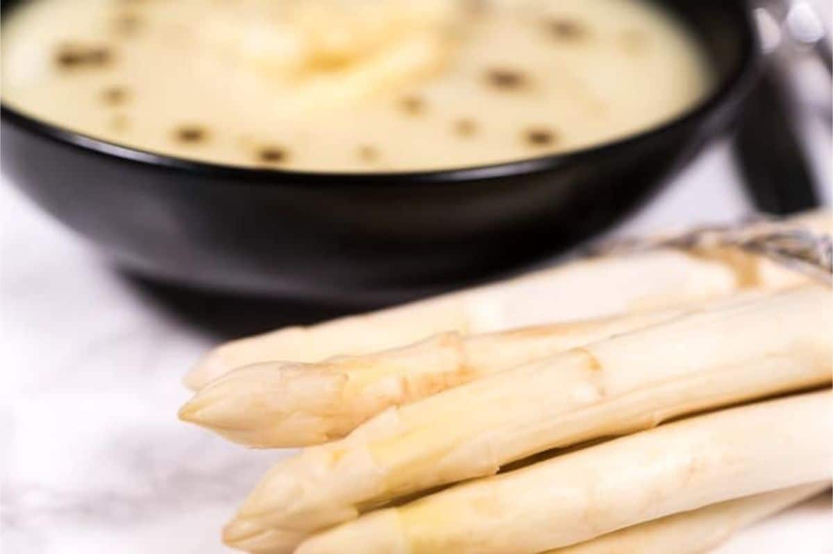 White asparagus with asparagus soup in the background