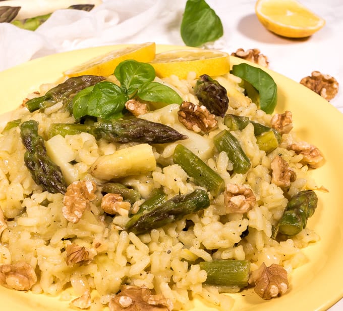 Vegan asparagus risotto with both green and white asparagus, topped with walnuts and basil