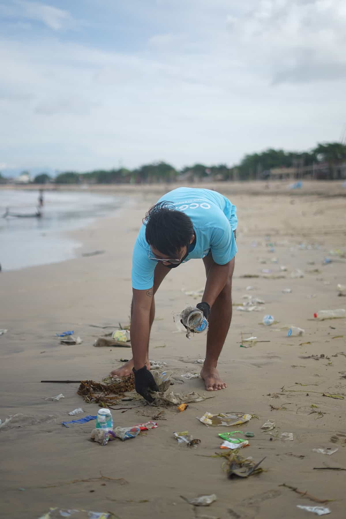 A man cleaning a beach of plastic waste