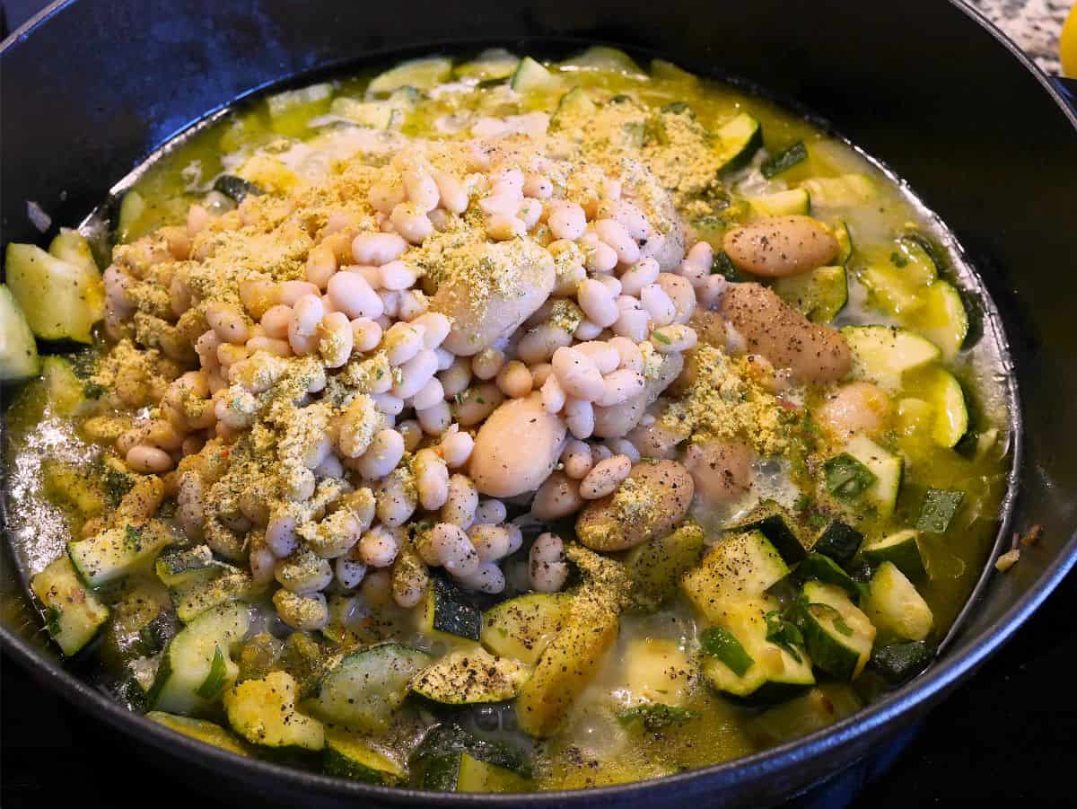 Butter beans and small white beans added to zucchini in a skillet